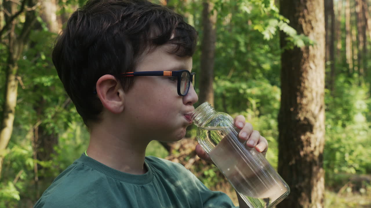 niño bebiendo agua en el bosque