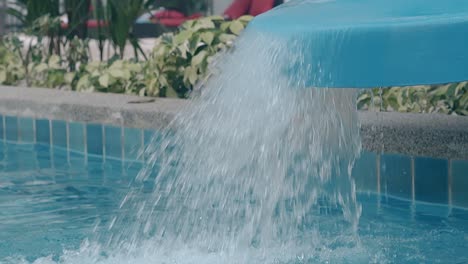 Agua-Clara-Cae-Desde-El-Tobogán-A-La-Piscina-En-Movimiento-Del-Resort