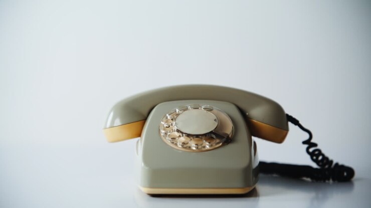 Gros plan d’un téléphone rotatif posé sur une surface dans un intérieur calme. Appareil rétro