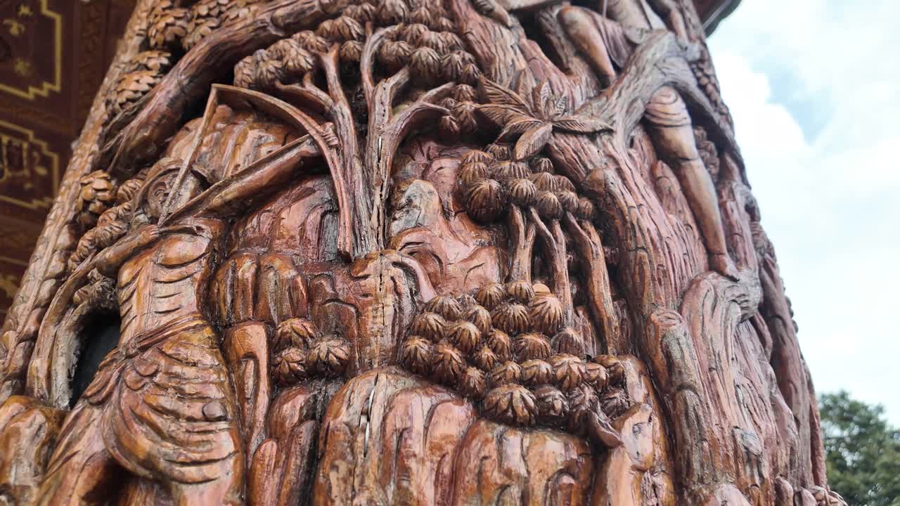 Intricate wood carving showcasing mythological figures and traditional Thai art on a temple pillar