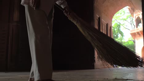 man sweeping dusty floor