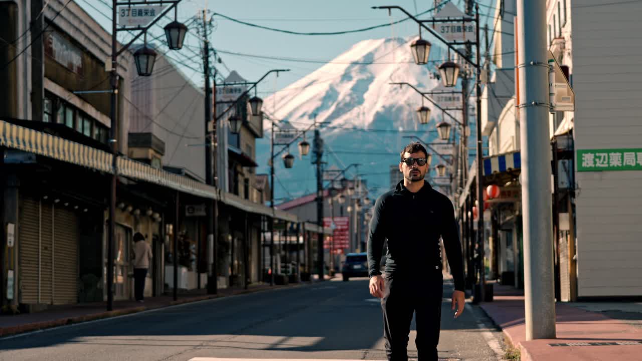 una escena cautivadora de un hombre caminando por la calle honcho en la ciudad de shizuoka, japón, con el majestuoso monte fuji cubierto de nieve en el fondo.