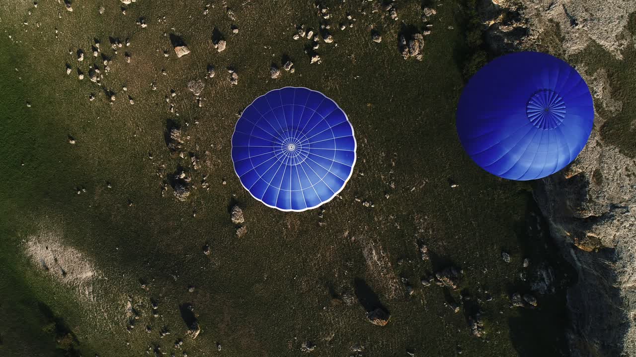 dos globos de aire caliente azules sobre un paisaje rocoso