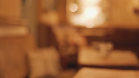 two dark stout beers on a wooden pub table are picked up, leaving a softly lit, warmly blurred background with inviting, ambient lighting and shallow focus