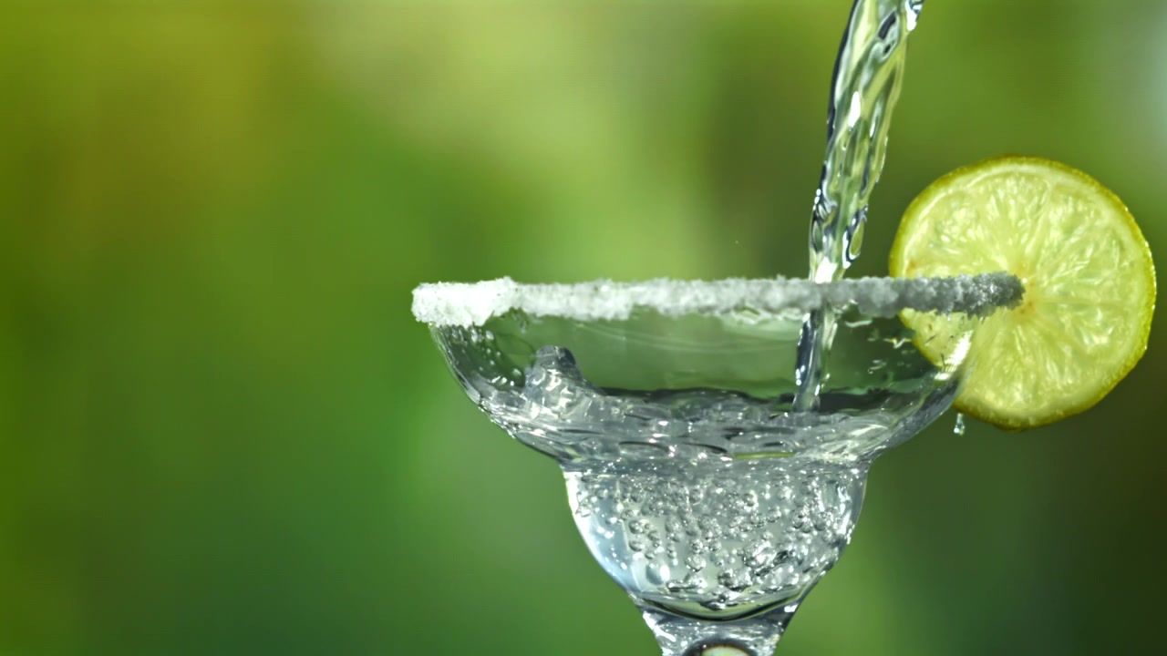Bevanda rinfrescante versata in un bicchiere da margarita con bordo salato e lime.