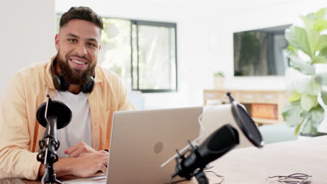 smiling man using laptop and microphone for podcasting in home office