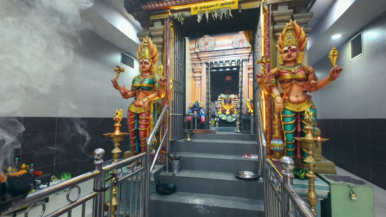 A beautifully adorned Hindu temple entrance with intricately crafted guardian statues, divine deities in the sanctum, and sacred incense smoke creating a spiritual and serene atmosphere
