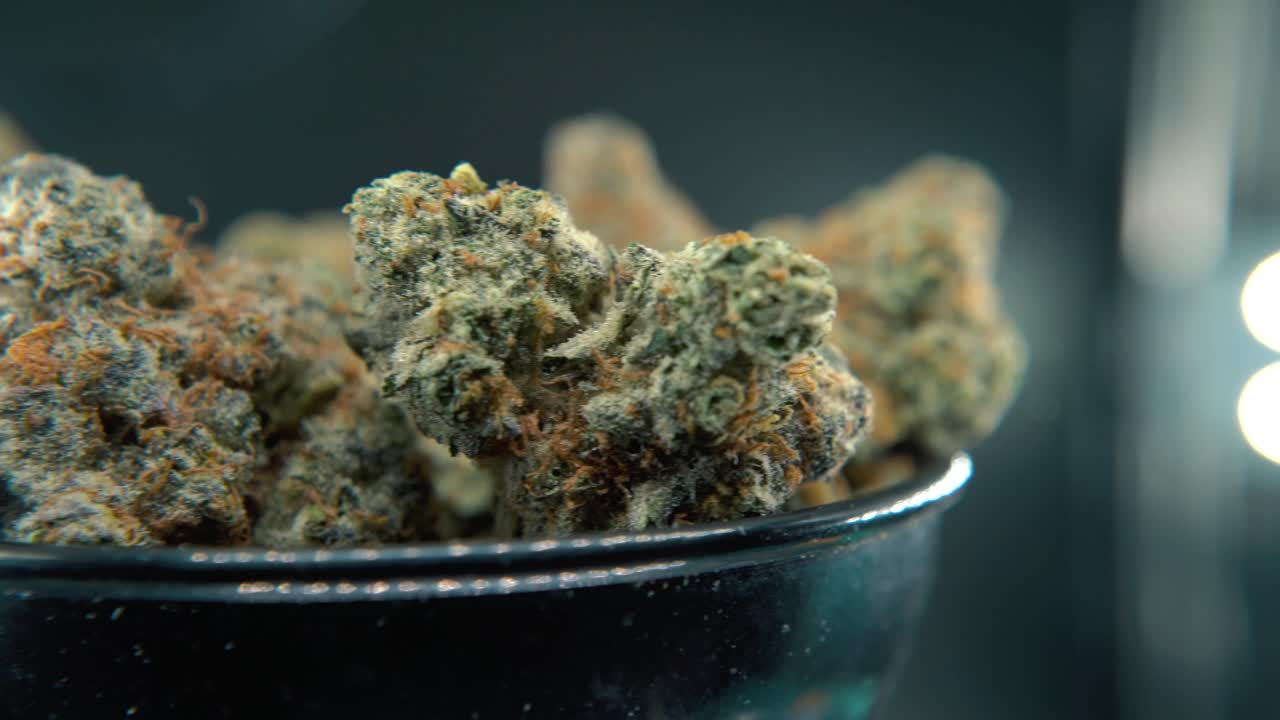 A macro smooth shot of a cannabis plant, hybrid orange strains, sativa ,marijuana flower, on a rotating stand, 4k video, slow motion, studio lighting