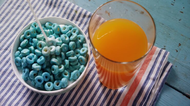 Latte versato in anelli di cereali con un bicchiere di succo 4k