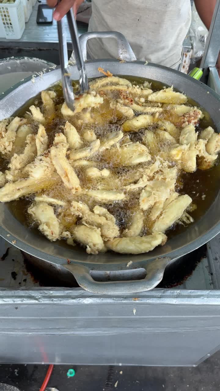 Friggere frittelle di banana croccanti in un grande wok.