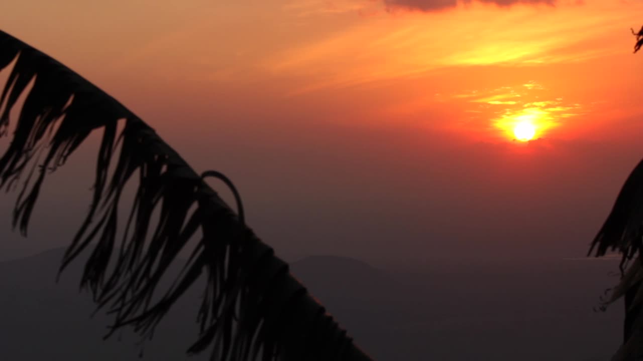 열대 풍경에서 피처럼 붉은 일몰을 일으키는 수평선 위의 장엄한 태양 설정, 팬 업