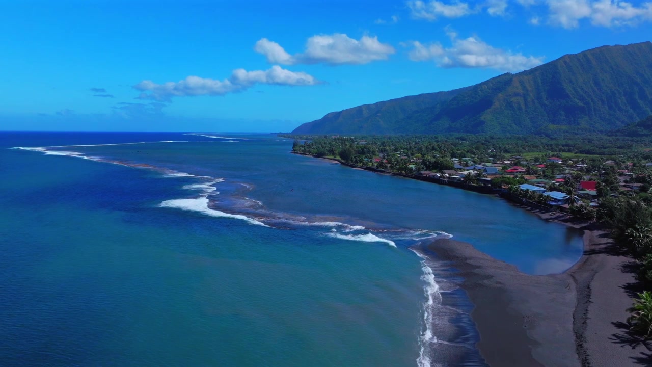Tahiti, scenografica spiaggia di sabbia nera di Taharuu, famosa località per il surf, costa della Polinesia Francese, vista aerea da drone, uccelli in volo, Papeete, Vaira'o, Oceano Pacifico meridionale, onde che si infrangono, surf break, movimento a ritroso.