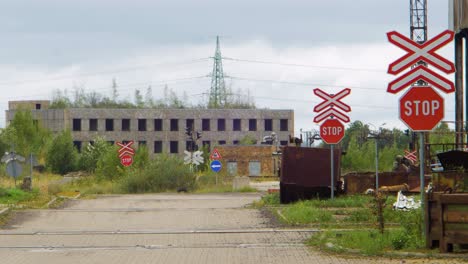 exterior view of abandoned soviet heavy metallurgy melting factory liepajas metalurgs territory, empty street, stop signs at railway, overcast day, wide shot