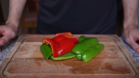 close-up of person showing peppers cut into pieces on a wooden board