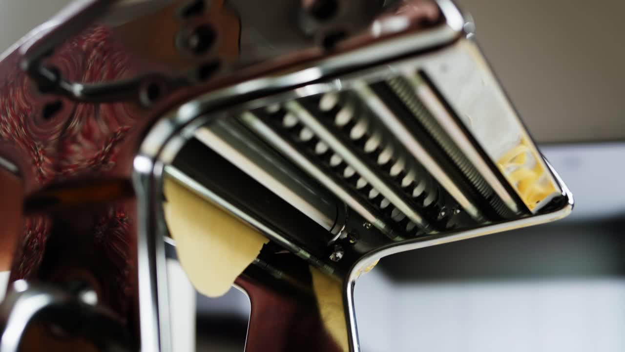 Close-up of Pasta Dough Being Rolled Through a Pasta Maker