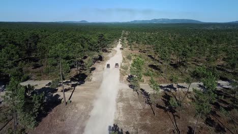 Two-classic-cars-race-down-an-empty-dirt-road-with-epic-view