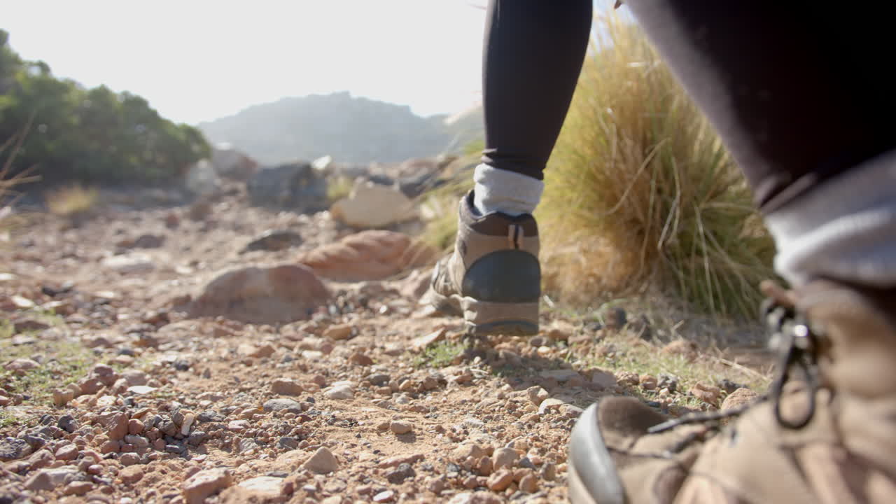 Hiking on rocky mountain trail, woman wearing hiking boots and leggings