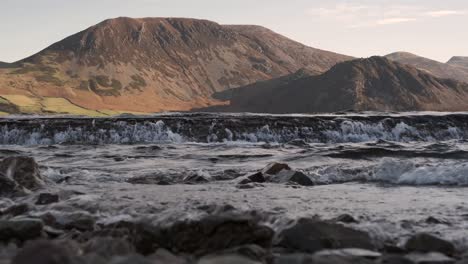 winter winds blow across the surface of ennerdale water in the lake district, cumbria, england with sunshine on the hills beyond