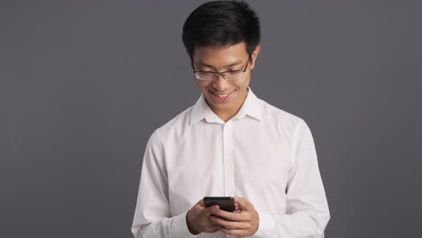 Asian-man-checking-smartphone-and-smiling.