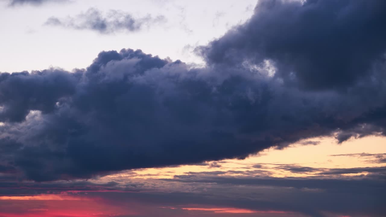 una gran nube oscura con un destello de luz del sol rojo que se pone, lapso de tiempo