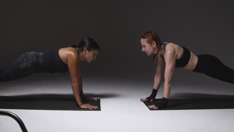 Studioaufnahme-Von-Zwei-Reifen-Frauen-In-Fitnesskleidung,-Die-Gemeinsam-Plankenübungen-Machen