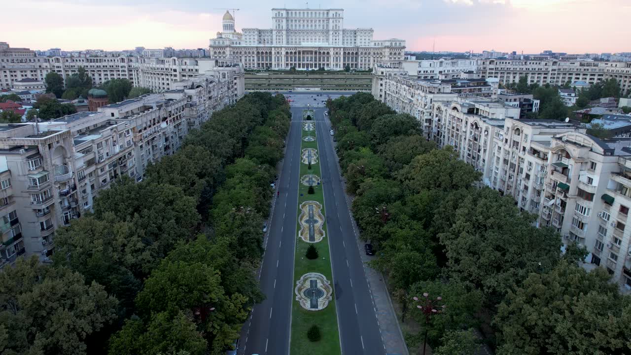 impresionante vista aérea en cámara lenta del palacio del parlamento en bucarest, rumania al atardecer, con cielo naranja y fuentes de agua bailando
