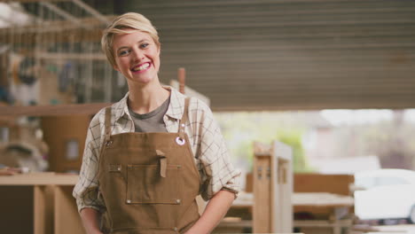 Retrato-De-Una-Aprendiz-Sonriente-Trabajando-Como-Carpintero-En-Un-Taller-De-Muebles