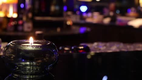 a lit candle in a bar with a blurred background