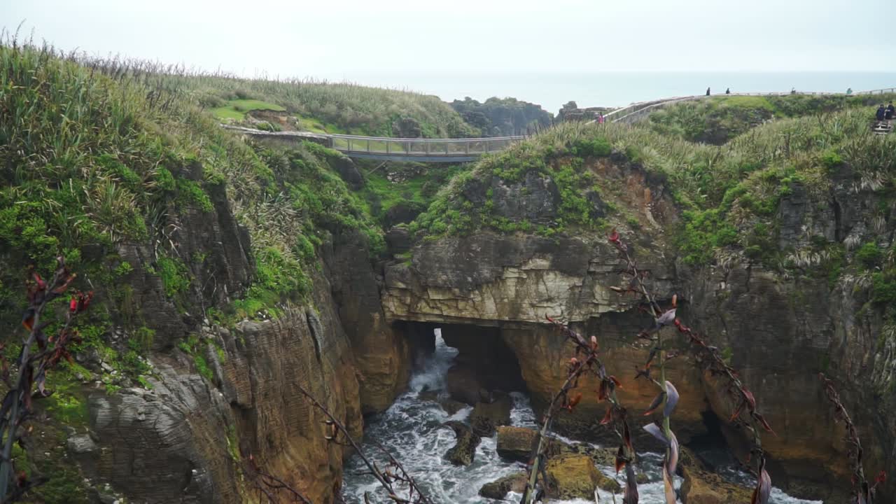 Ocean tidal waves hitting Punakaiki Pancake Rocks, New Zealand with tourists in background