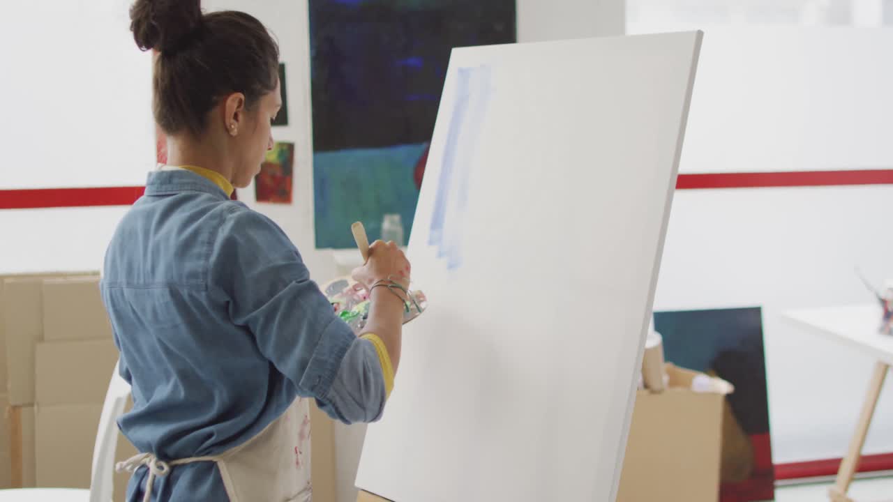 video de una artista biracial pintando en un estudio