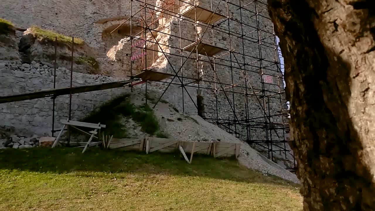 Revealing shot of metallic scaffolding against an old ruins wall