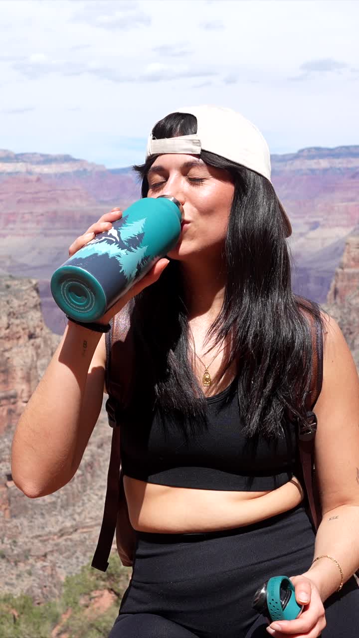 Donna felice beve acqua da una bottiglia in un suggestivo paesaggio canyon