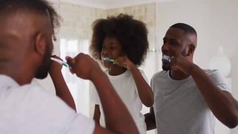 Hija-Afroamericana-Y-Su-Padre-Mirándose-En-El-Espejo-Cepillándose-Los-Dientes-Juntos-En-El-Baño