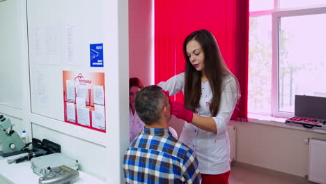 doctor and patient in ophthalmology clinic. attractive female doctor ophthalmologist checking the eye vision of handsome young man in modern clinic