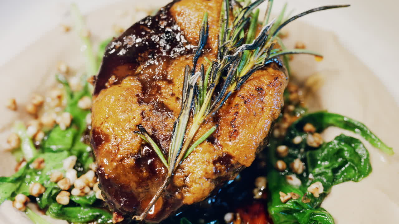 Close up of a beautifully plated beef filet, topped with a golden crust and garnished with rosemary