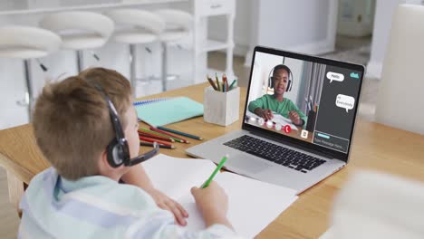 Schoolboy-using-laptop-for-online-lesson-at-home,-with-schoolboy-and-webchat-on-screen