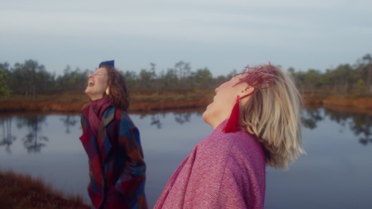 Close-up shoot of two women in artistic outfit laughing in the swamp.