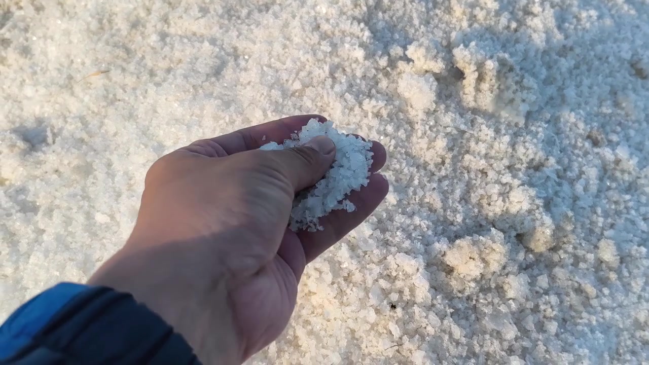 Hånd der rører og holder rå havsaltkrystaller.