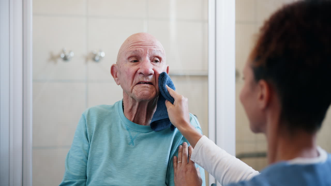 Nurse assisting senior man with washing face