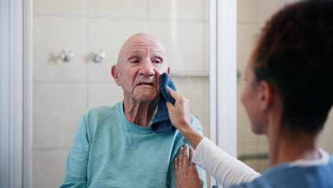 nurse assisting senior man with washing face