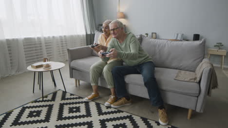 Happy-Middle-Aged-Arabic-Woman-And-Senior-Man-Playing-Video-Game-While-Sitting-On-Sofa-At-Home-1