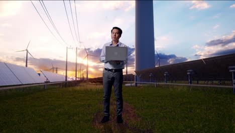 full body of an asian male professional worker with his laptop with solar panel and wind turbines, he observes by looking around before he come to concentrating with his laptop