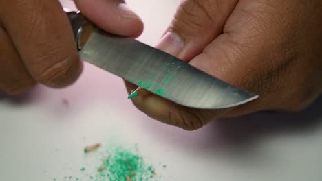 imágenes de manos afilando lentamente un lápiz y algunos lápices de colores con un cuchillo afilado