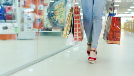 woman's legs in fashionable shoes on a high platform go to the mall it carries a lot of packages for