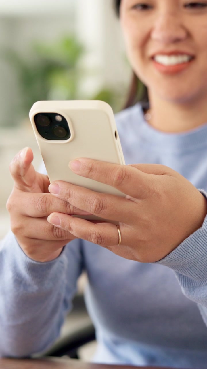 Donna sorridente che usa lo smartphone in un ambiente interno luminoso