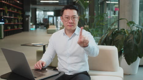 serious mature businessman shakes finger and saying no be careful and giving advice in office lobby