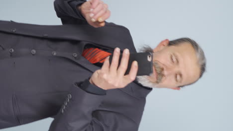 video vertical de un viejo hombre de negocios bailando con el teléfono en la mano.