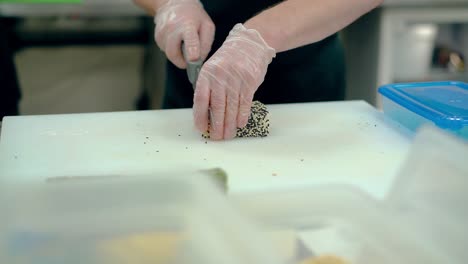 cook cuts a japanese roll with sesame seeds