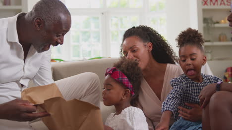 multi-generation family celebrating christmas at home opening presents together