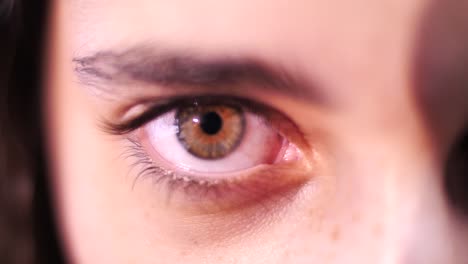 Woman-opens-brown-eye-close-up